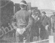 
（上）米軍憲兵の嚴重な監視の下に、敵側の捕虜は重々しい足どりで車にのりこんでいる。

